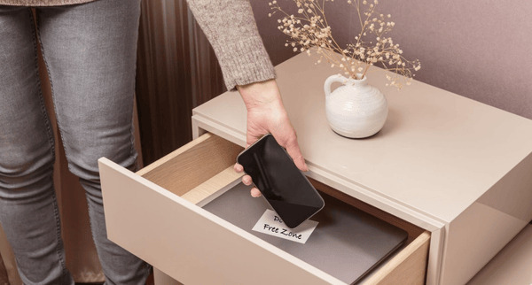 Woman placing her phone in a drawer at home to disconnect from technology and create space for mindfulness and mental clarity