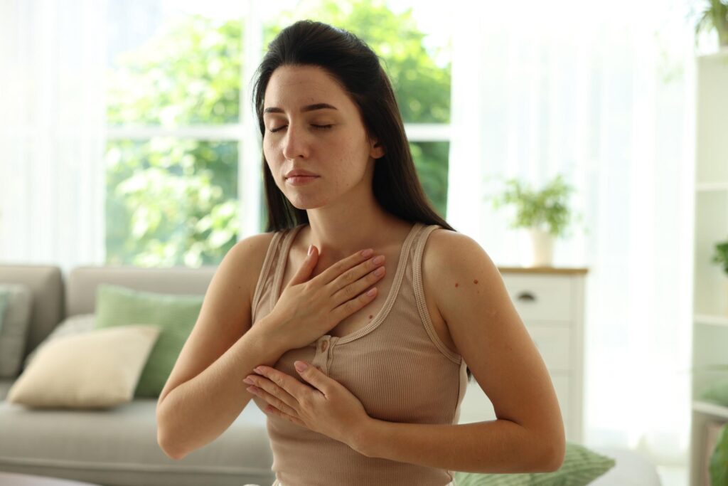Woman sitting at home practicing deep breathing to calm anxiety and emotional overwhelm